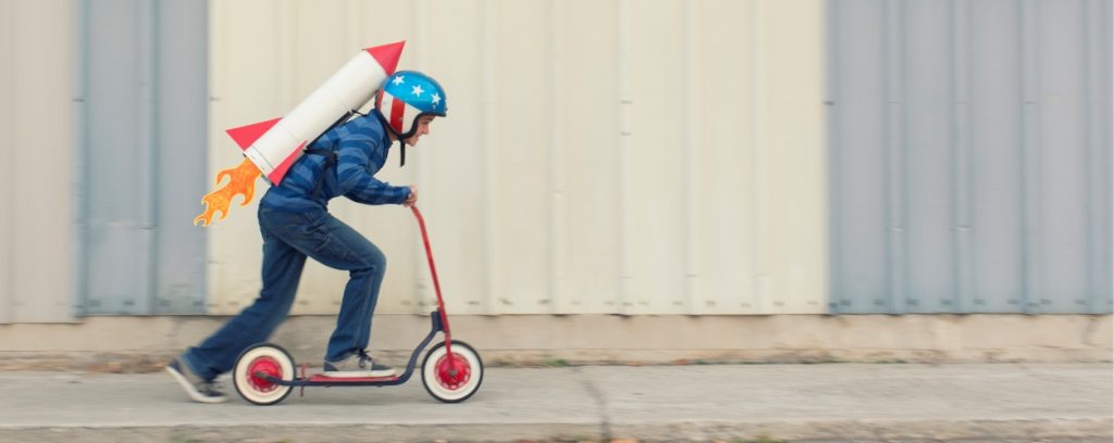 Kid dressed as Evel Knievel speeding off on his scooter